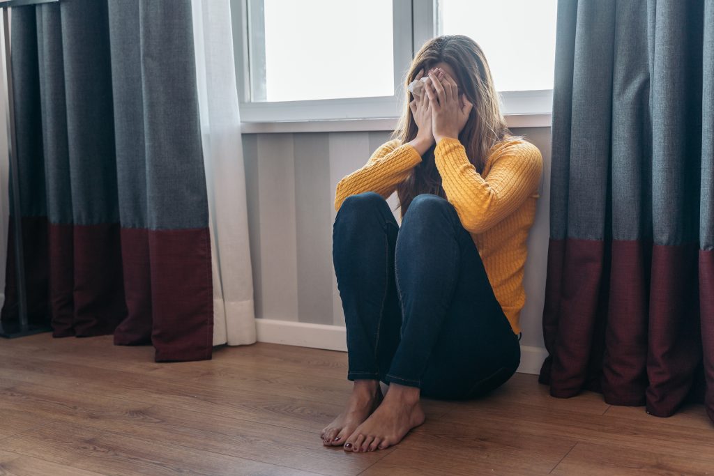 Young woman sitting on the floor after being abused by her partner. Concept of violence and abuse against women.