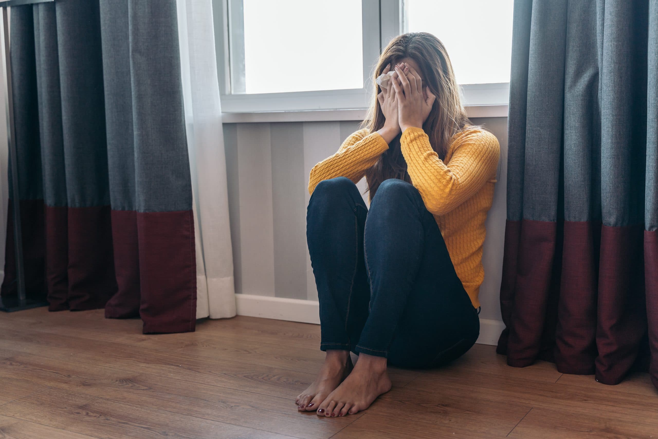 Young woman sitting on the floor after being abused by her partner. Concept of violence and abuse against women.