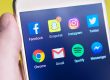 Person holding a phone with social media applications visible.