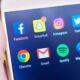 Person holding a phone with social media applications visible.