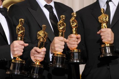 Four white men each holding an Oscar award.