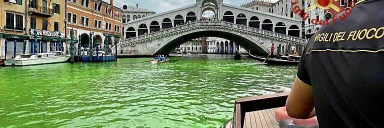 Bright green water flowing under the Rialto Bridge in Venice, Italy.