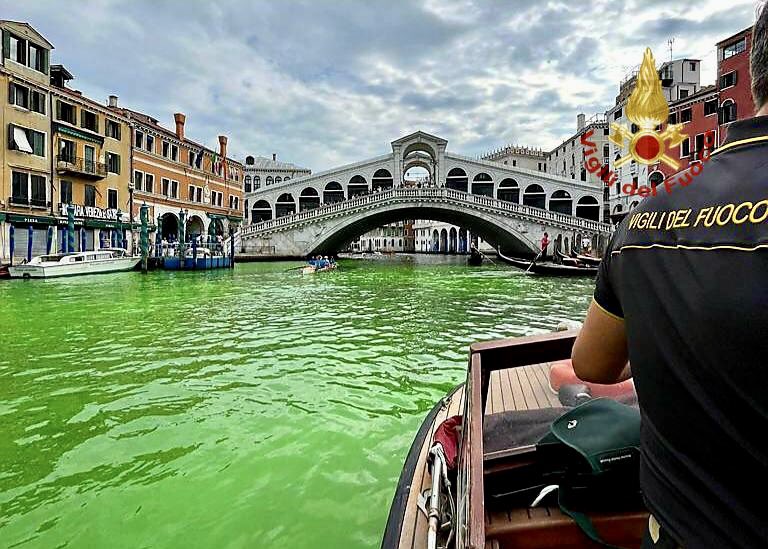 Bright green water flowing under the Rialto Bridge in Venice, Italy.