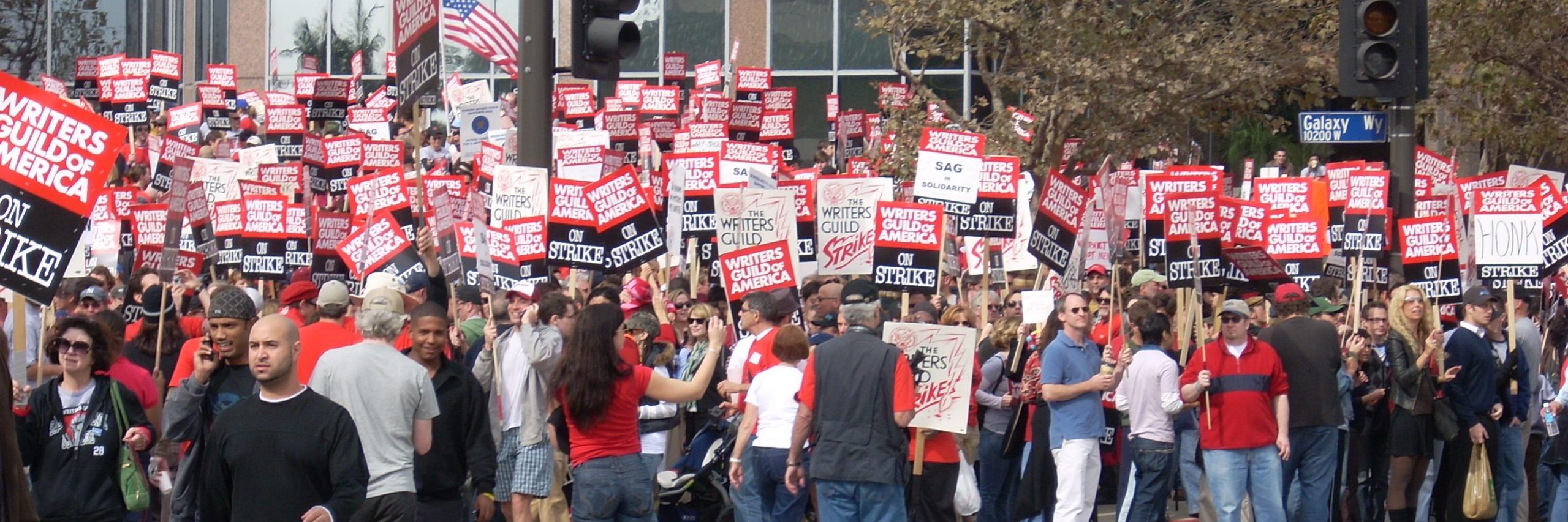 Workers marching with red and white signs during the Hollywood writers strike.