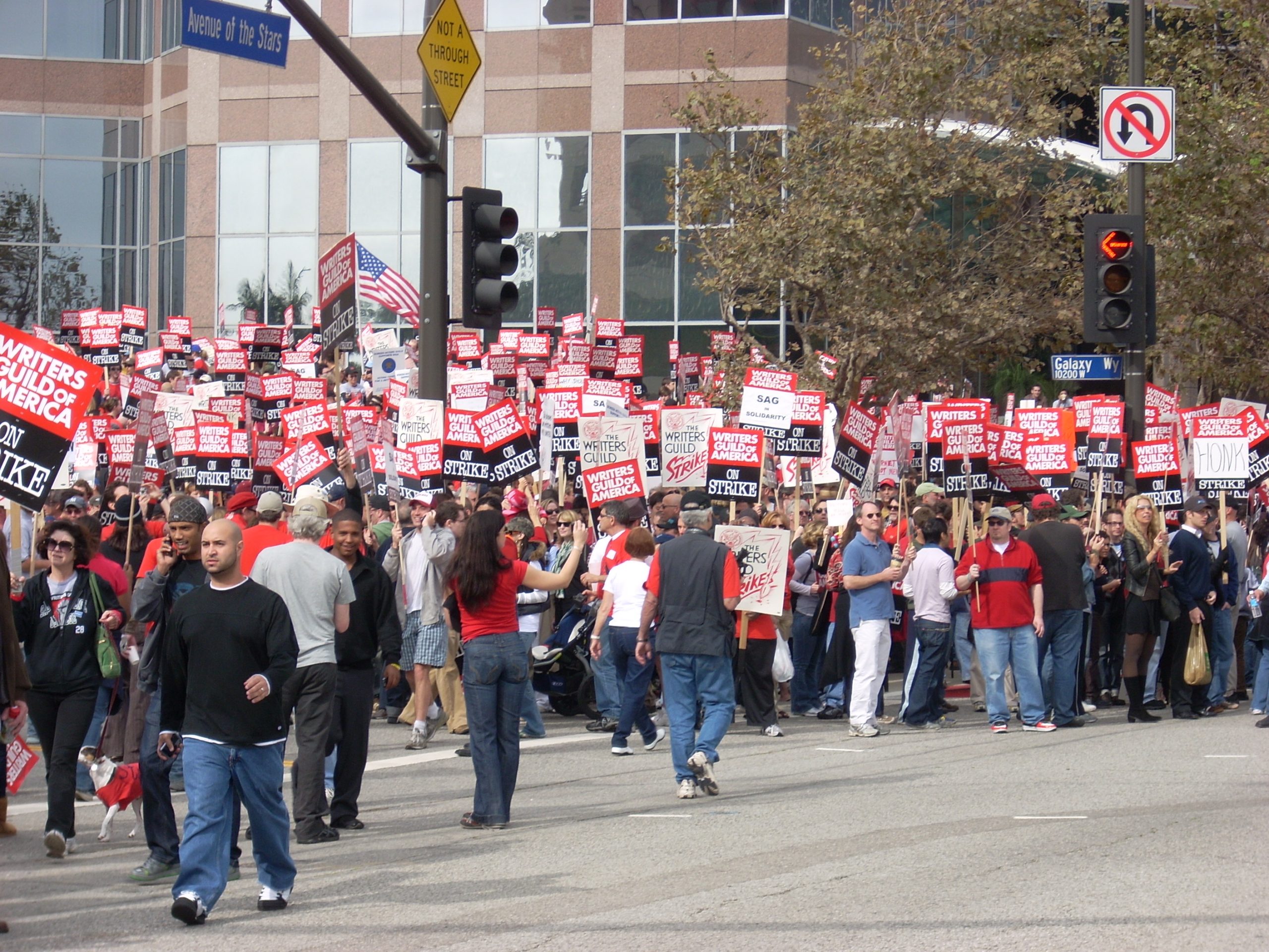 Workers marching with red and white signs during the Hollywood writers strike.