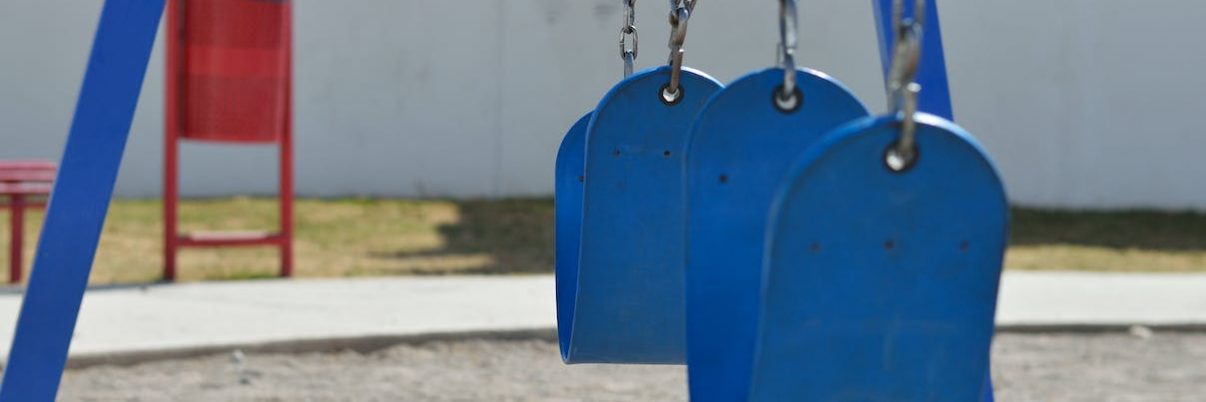 A blue playground swing set with empty seats.