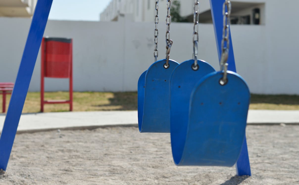 A blue playground swing set with empty seats.