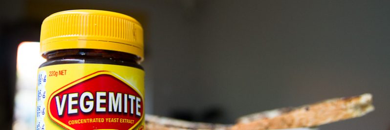 A jar of vegemite on a benchtop with toast in the background
