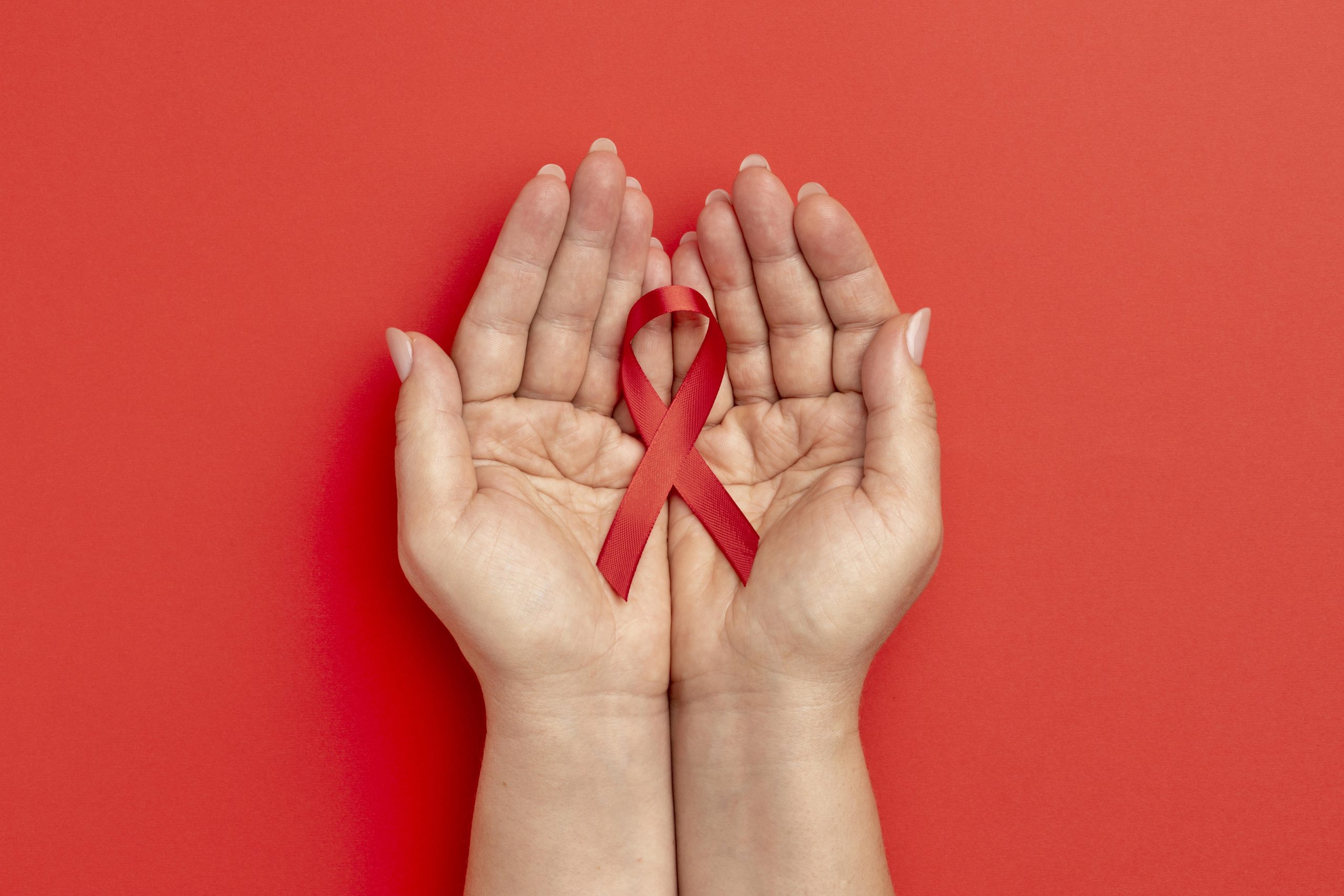 A person holding a red ribbon for World Aids Day