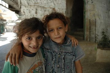 Two Palestinian children with their arms wrapped around each other.