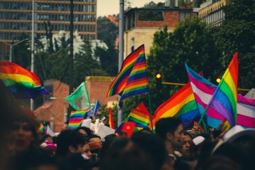 A crowd of people holding a variety of flags that support the LGBTQ+ community