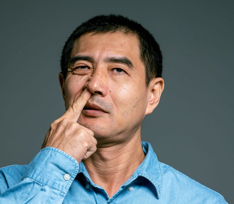 A man picking his nose, which may contribute to Alzheimer’s disease.