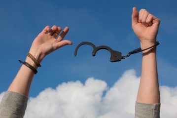 unlocked handcuffs on a person's hands.