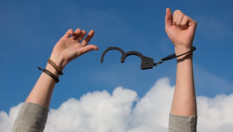 unlocked handcuffs on a person's hands.