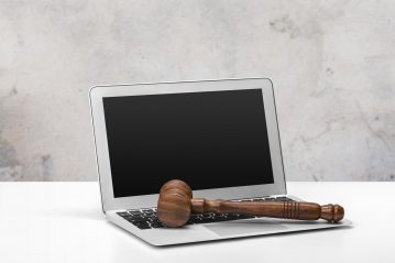 An open laptop with a court gavel across the keyboard. The AI Act will be put into place via the European Union.