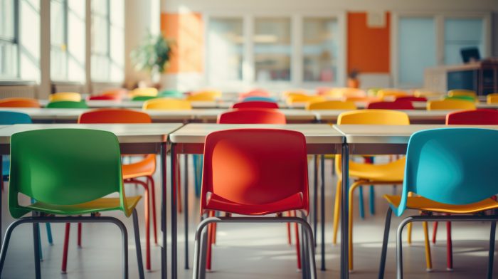 Colorful chairs surround tables in bright, vibrant classroom. Australia's literacy levels require government action. Image Source: Rorozoa, via Freepik