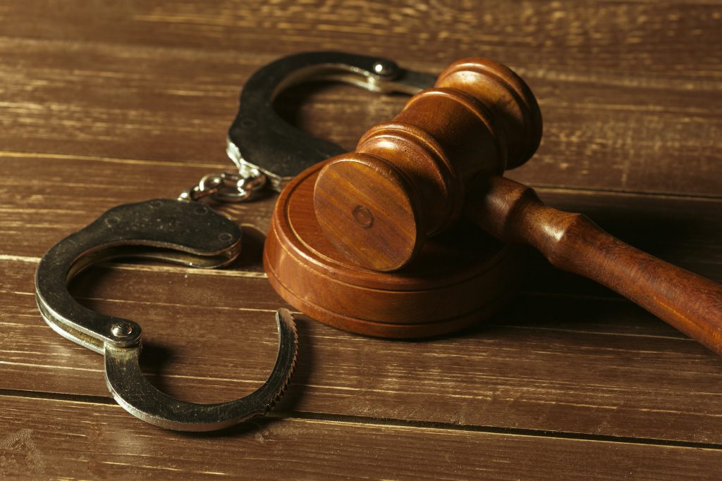 an image of a judge's mallet and handcuffs, symbolic of the guilty sentence of the tesla driver who was in a hit and run. Image source: fabrikasimf, via freepik.