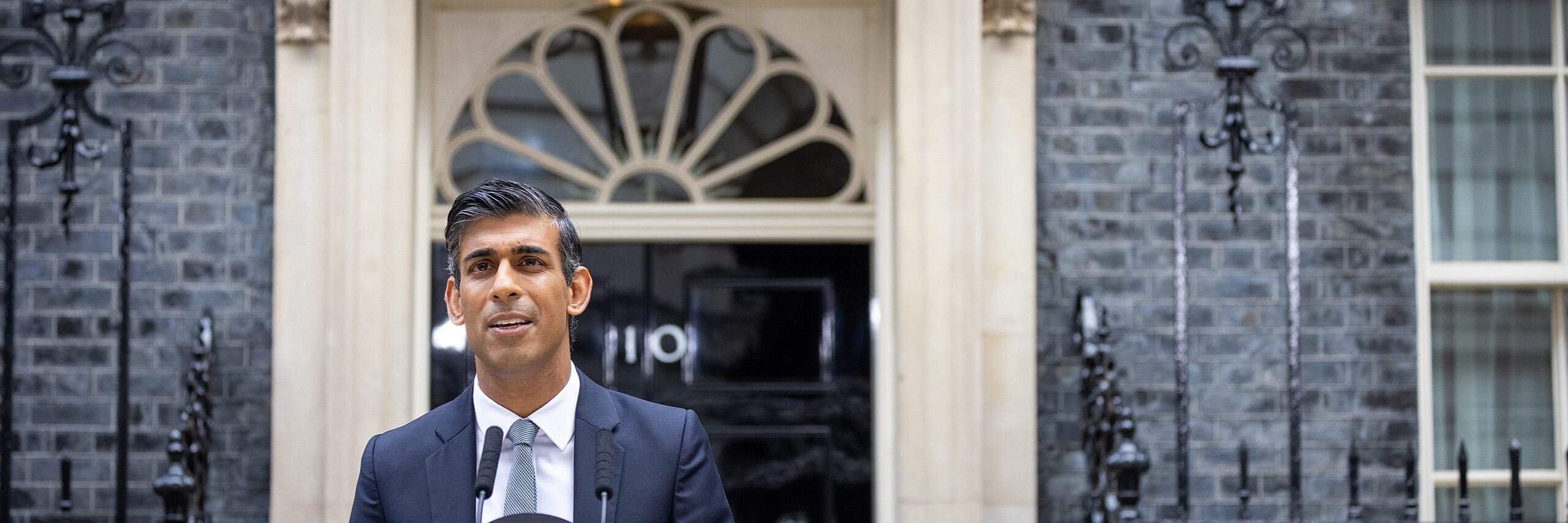 An image of British Prime Minister Rishi Sunak standing outside 10 Downing Street. He is currently handling allegations of improper gambling within his staff. Image source: Lauren Hurley, via: Wikimedia Commons