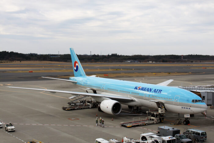 An image of a Korean Air aircraft parked on a runway at Narita International Airport. The airplane is pale blue on the top and white below, with the name 'Korean Air' on the side. Image source: Kentaro Iemoto, via Wikimedia Commons.