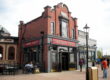 An image of the Raglan Road Irish Pub in Disney Springs, a section of Walt Disney World in Orlando, Florida. The building is red brick with black trim, and a large red sign states the restaurant name over the door. Image source: berkielynn, via Wikimedia Commons