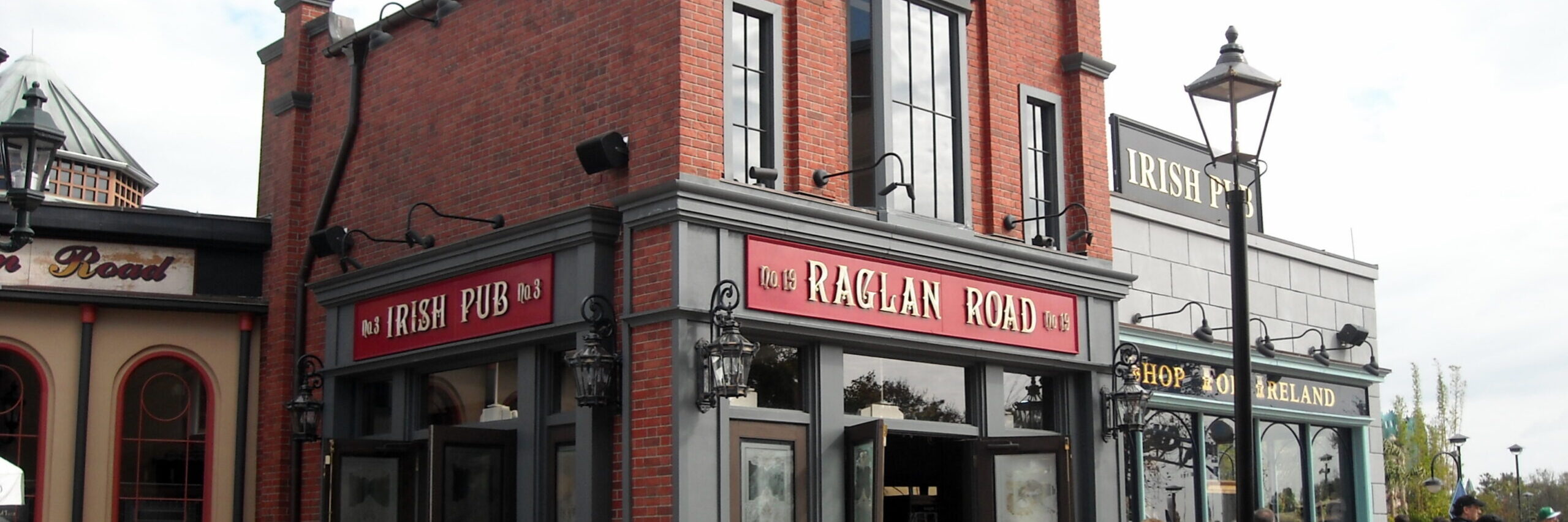 An image of the Raglan Road Irish Pub in Disney Springs, a section of Walt Disney World in Orlando, Florida. The building is red brick with black trim, and a large red sign states the restaurant name over the door. Image source: berkielynn, via Wikimedia Commons