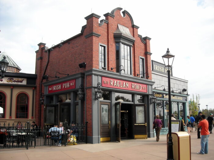 An image of the Raglan Road Irish Pub in Disney Springs, a section of Walt Disney World in Orlando, Florida. The building is red brick with black trim, and a large red sign states the restaurant name over the door. Image source: berkielynn, via Wikimedia Commons