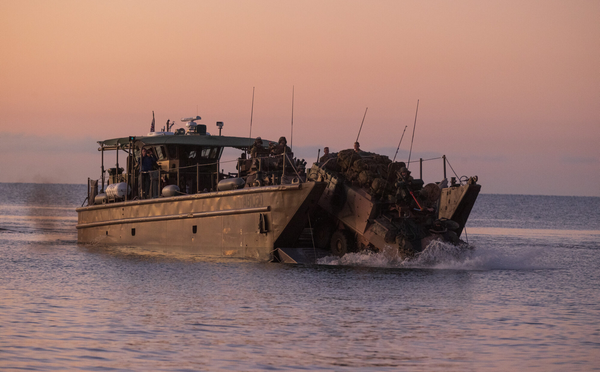 A light armoured vehicle disembarks from a landing craft on Forrest Beach, Far North Queensland, during Exercise Talisman Sabre 2021. Photo: Defence Department