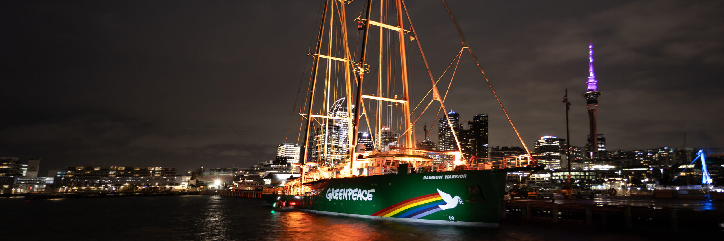 The Rainbow Warrior lights up at dawn today (July 10, 2025) in Auckland Harbour. Photo: Bryce Groves/Greenpeace