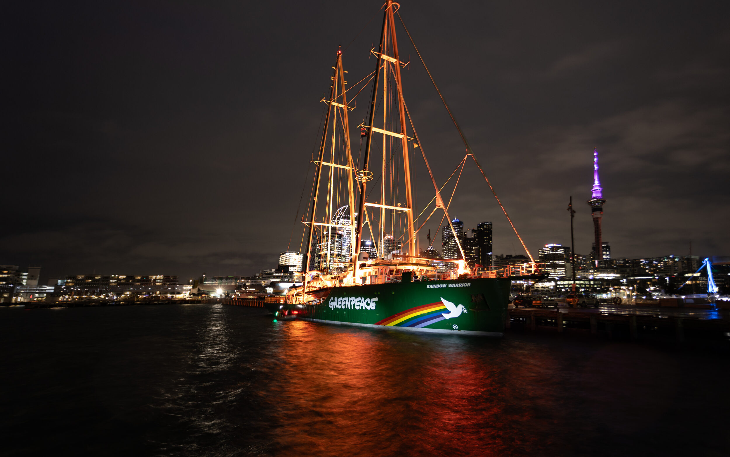 The Rainbow Warrior lights up at dawn today (July 10, 2025) in Auckland Harbour. Photo: Bryce Groves/Greenpeace