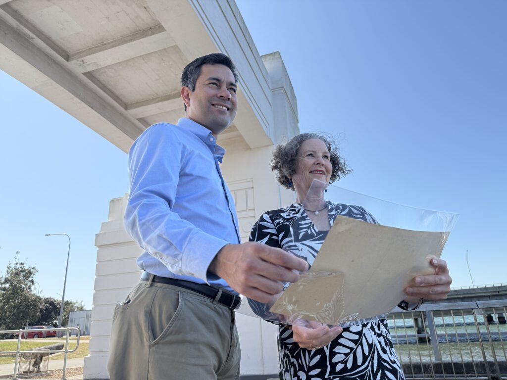 Moreton Bay Councillor Karl Winchester and Julie Hornibrook stand at the Hornibrook Bridge portal at Clontarf with the original plans for the Hornibrook Bridge. Photo: Moreton Bay City Council