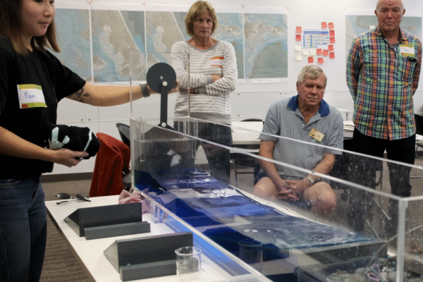 Coastal residents view a wave tank demonstration of protection against tidal impacts. Photo: MBCC