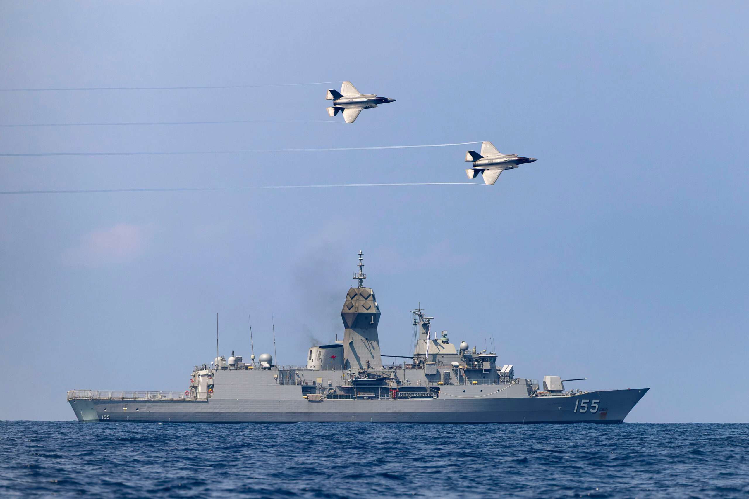 RAAF F-35 jets fly over the HMAS Ballarat off the coast of Malaysia last year as part of Exercise Bersama Lima 25. Photo: Department of Defence.