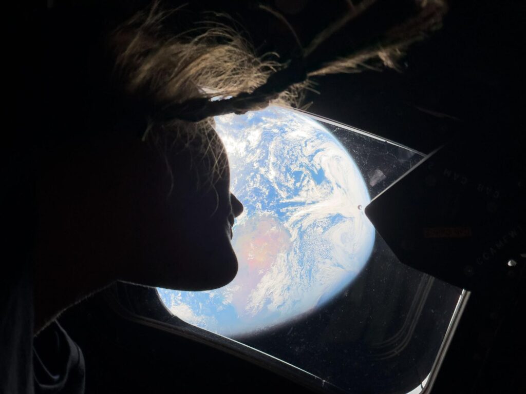 Orion astronaut Christina Koch peers out of a main cabin window back at Earth, as they head towards the moon. Photo: NASA.