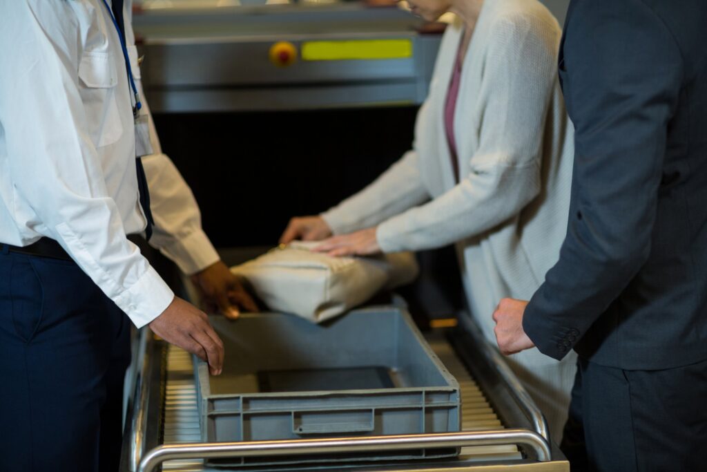 Adelaide Airport biosecurity: staff and a traveller at a baggage screening machine