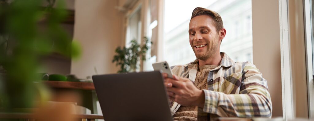 BPAY View land tax: a man checks his phone with a laptop open beside him