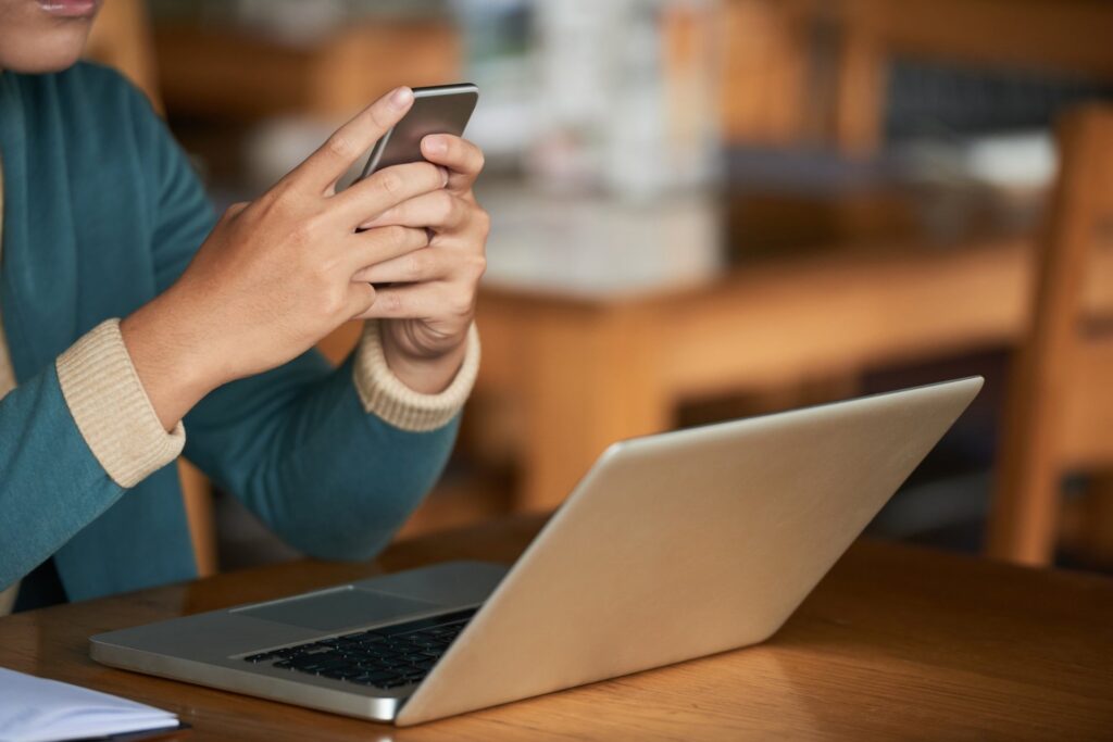Person using a phone beside a laptop, illustrating digital asset platforms