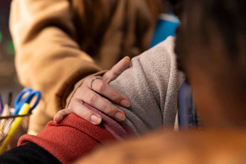 Hand resting on a colleague’s shoulder in support, care sector pay funding