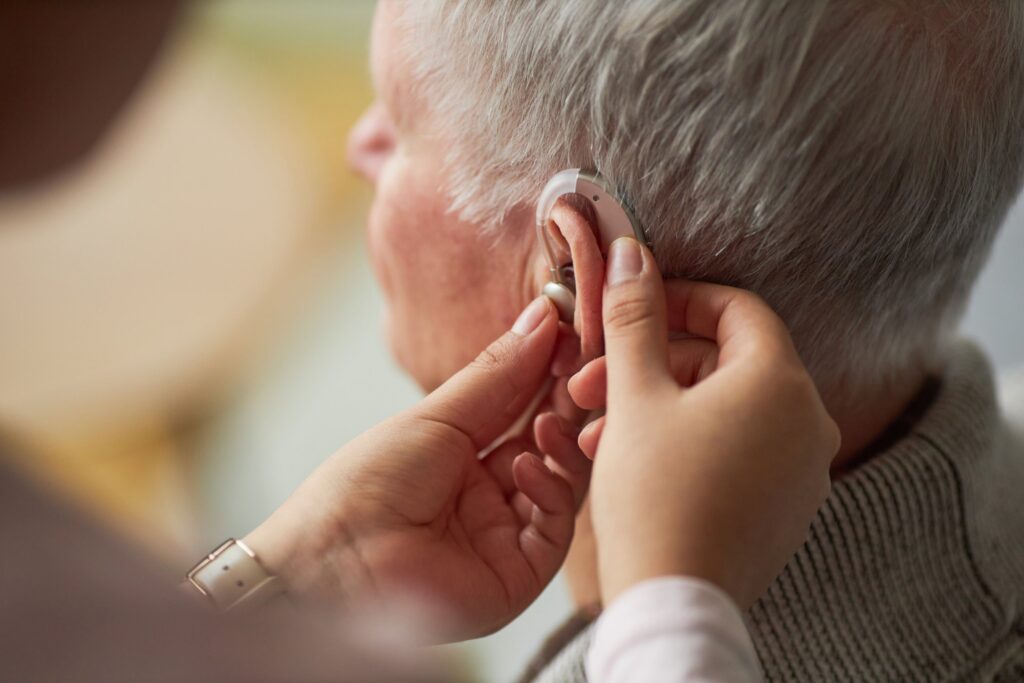 Health professional fitting a hearing aid on an older patient, Hearing Services Program self-assessment