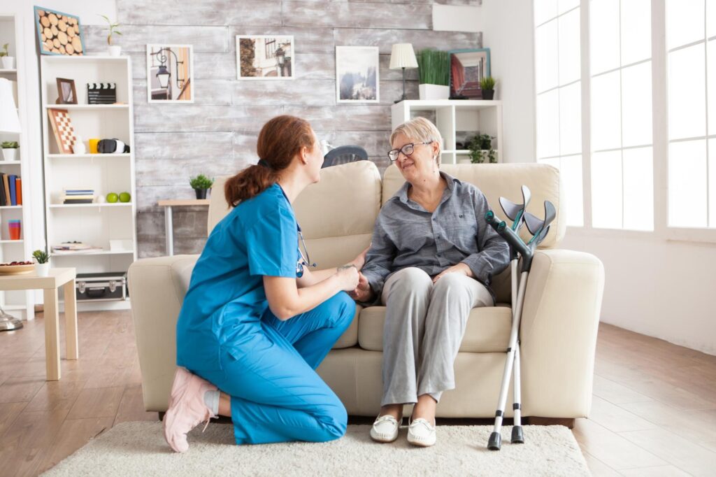 Home care nurse holding hands with an older woman at home, illustrating the End-of-Life Pathway