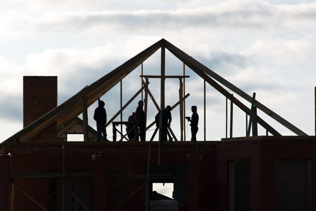 Silhouetted builders on a timber roof frame, illustrating Key Apprenticeship Program apprentices on a housing construction site