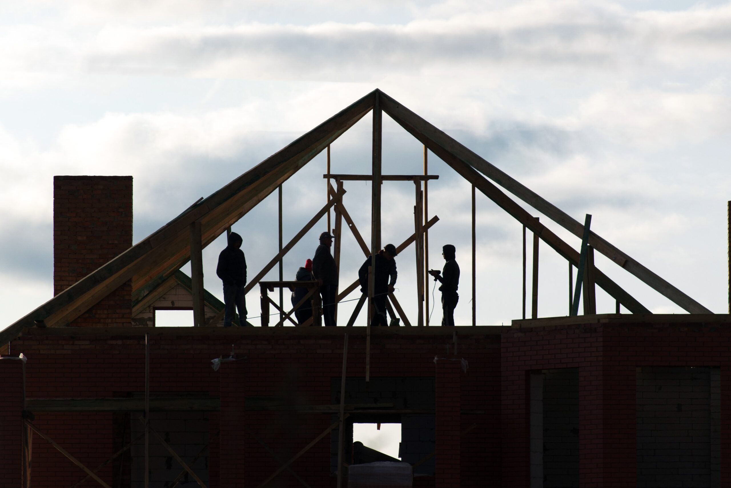 Silhouetted builders on a timber roof frame, illustrating Key Apprenticeship Program apprentices on a housing construction site