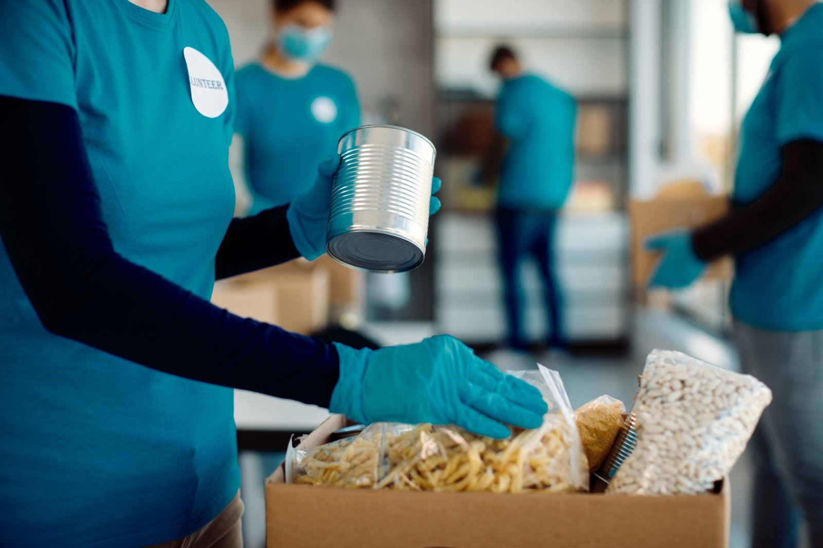 Volunteers packing pasta, beans and canned goods into a food relief box, illustrating National Debt Helpline and emergency relief funding